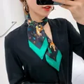 Macro view of black floral silk twilly scarf with tiger print and green contrast borders - Black Green Base