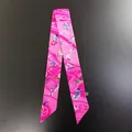 Vista detallada del pañuelo twilly de seda rosa con estampados artísticos y textura suave - Rosa