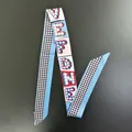Detail of a blue silk twilly scarf featuring artistic letters and geometric floral patterns - Long Ribbon / Dark Blue