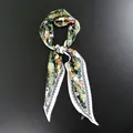Primer plano de un pañuelo de seda con estampado floral verde y un borde contrastado - 33x105cm / Negro