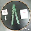 Detailed view of dark green silk twilly featuring golden chain prints on a black tray - Dark Green Chain (S177-27)