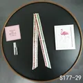 Detailed view of cream satin twilly scarf with gold horsebit chain on black wooden tray - Cream Red Green Stripe (S177-29)
