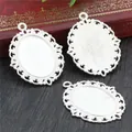 Three pieces of vintage silver oval cameo settings with filigree edges on a rustic desk - Silver