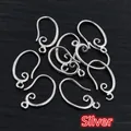 Macro shot of silver-plated copper earring hooks with spiral detail on wood background - Silver