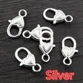 Fünf herzförmige silberne Karabinerverschlüsse für DIY-Schmuck auf dunklem Holzgrund - Gestreift / Silber