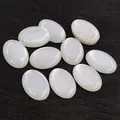 Macro detail of 10 white oval cabochon resin stones on a rustic wood background - Milky White Style (G7-04)