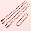 Detail of 2mm bronze bead chains with connectors for tags and accessories on pink surface - Copper