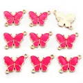 Vista macro de colgantes de mariposa dorados con esmalte rosa y anillos dobles - Paquete de 10 / Rosa rojo
