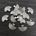 Group of vintage silver fan-shaped metal pendants for DIY jewelry on wood background - Antique Silver