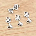 Set mit vier silbernen Katzenanhängern für DIY-Schmuck auf hölzernem Hintergrund - Antiksilber