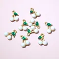 Close-up of gold cherry charms with green enamel leaves and white beads for DIY jewelry - Pearlescent White Cherry Style (E6-65)