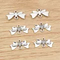 6 Vintage-Silber-Schleifenanhänger aus Legierung für DIY-Schmuck auf Holzhintergrund - Antiksilber