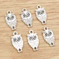 Set of six silver alloy owl pendants for DIY jewelry making on wooden background - Antique Silver
