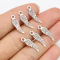 Silver alloy wing charms for DIY jewelry making shown on finger for scale - Antique Silver