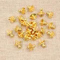 Macro view of gold metal pacifier charms for DIY necklaces on a textured linen fabric - Gold