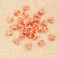 Macro shot of rose gold pacifier charms for DIY jewelry making on beige fabric - Rose Gold