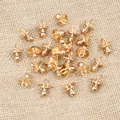Detailed macro view of multiple gold pacifier-shaped alloy charms for DIY jewelry making - KC Gold
