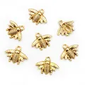 Detailed close-up of seven golden bee alloy charms for DIY necklace and bracelet jewelry - Antique Gold