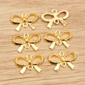 Detail of six gold alloy bow pendants for DIY jewelry making on a light wooden background - Gold