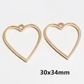Close-up of heart shaped gold alloy jewelry frames with 30x34mm dimension labels - Heart / 30x34mm