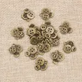 Antieke bronzen drievoudige knoophangers voor DIY-sieraden op een achtergrond van jute - Brons