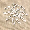 Silver safety pin charms for DIY jewelry making displayed on rustic burlap fabric - 19x6mm