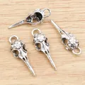 Set of four antique silver bird skull pendants with floral carvings on wood background - Antique Silver