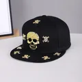 Close-up of golden skull and crossbones studs on a black flat brim hip-hop cap - Adjustable / Skull-Black