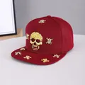 Detail of burgundy snapback hat featuring gold metal skull charms and flat brim hip-hop style - Adjustable / Skull-Wine Red
