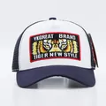 Dettaglio di un cappello trucker blu e bianco con toppa ricamata a forma di tigre - Regolabile / Occhio di Tigre Tesa Bianco Blu Notte