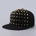 Detail of a black flat-brim snapback hat featuring shiny gold metal conical rivets - Gold Rivets