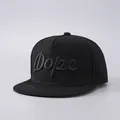 Macro detail van het 3D geborduurde Dope-schrift op een zwarte katoenen snapback pet - Effen Zwart Met Zwart Letterborduurwerk