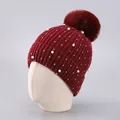 Detail of burgundy knit beanie featuring faux pearls, rhinestones and a fluffy fur pom-pom - One Size / Burgundy