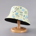 Detail view of the yellow floral bucket hat with blue daisies on a wooden hat stand - Pale Yellow Blue Daisy Print (27#)