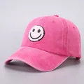 Detailed close-up of pink washed cotton baseball cap with fuzzy smiley face patch - Rose Red Smiley