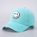 Close-up of a light blue cotton baseball cap with a white embroidered smiley face patch - Light Blue Smiley