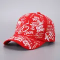 Close-up of red baseball cap with white street-style graffiti letters and ribbon details - Red-B52