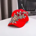 Red baseball cap with floral embroidery and rhinestones in a top-down view display - Adjustable / Red