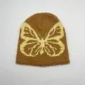 Dettaglio della texture in peluche del berretto marrone con motivo jacquard a farfalla gialla - Taglia unica / Farfalla Marrone