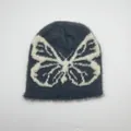 Vista dettagliata del berretto in morbido peluche grigio con motivo jacquard a farfalla bianca - Taglia unica / Farfalla Grigio Scuro