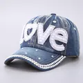 Detailed view of the sparkling rhinestone Love lettering and pearls on a blue denim cap - Pearl Rhinestone LOVE Style / Denim Blue Pearl Rhinestone LOVE