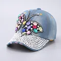 Detail of blue denim baseball cap featuring colorful rhinestone butterfly and crystal brim - Full Rhinestone Brim / Light Blue Butterfly