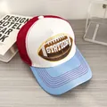 Dettaglio del cappellino trucker tricolore con ricamo rugby su un tavolo di legno - Regolabile / Bianco Tesa Blu Chiaro (Rugby)