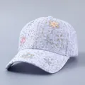 Detail der fliederfarbenen Spitzen-Basecap mit glitzernden Strasssteinen und 3D-Blumen - Blumen-Stil / Lila
