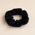 Detailed close-up of a soft black velvet scrunchie showing fabric texture and elastic structure - Black
