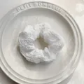 Dettaglio dell'elastico per capelli bianco con trama a bolle su piatto di ceramica - Bianco
