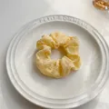 Dettaglio di un morbido elastico giallo pallido su un piatto di ceramica bianca - Giallo