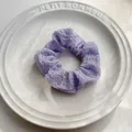 Dettaglio macro dello scrunchie lavanda stropicciato su un piatto decorativo in ceramica - Viola