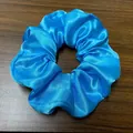 Détail d'un chouchou en satin bleu à texture soyeuse sur un fond en bois sombre - Bleu ciel