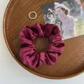 Detail eines bordeauxroten Satin-Haargummis auf einem Holztablett mit Vintage-Flair - Burgunderrot